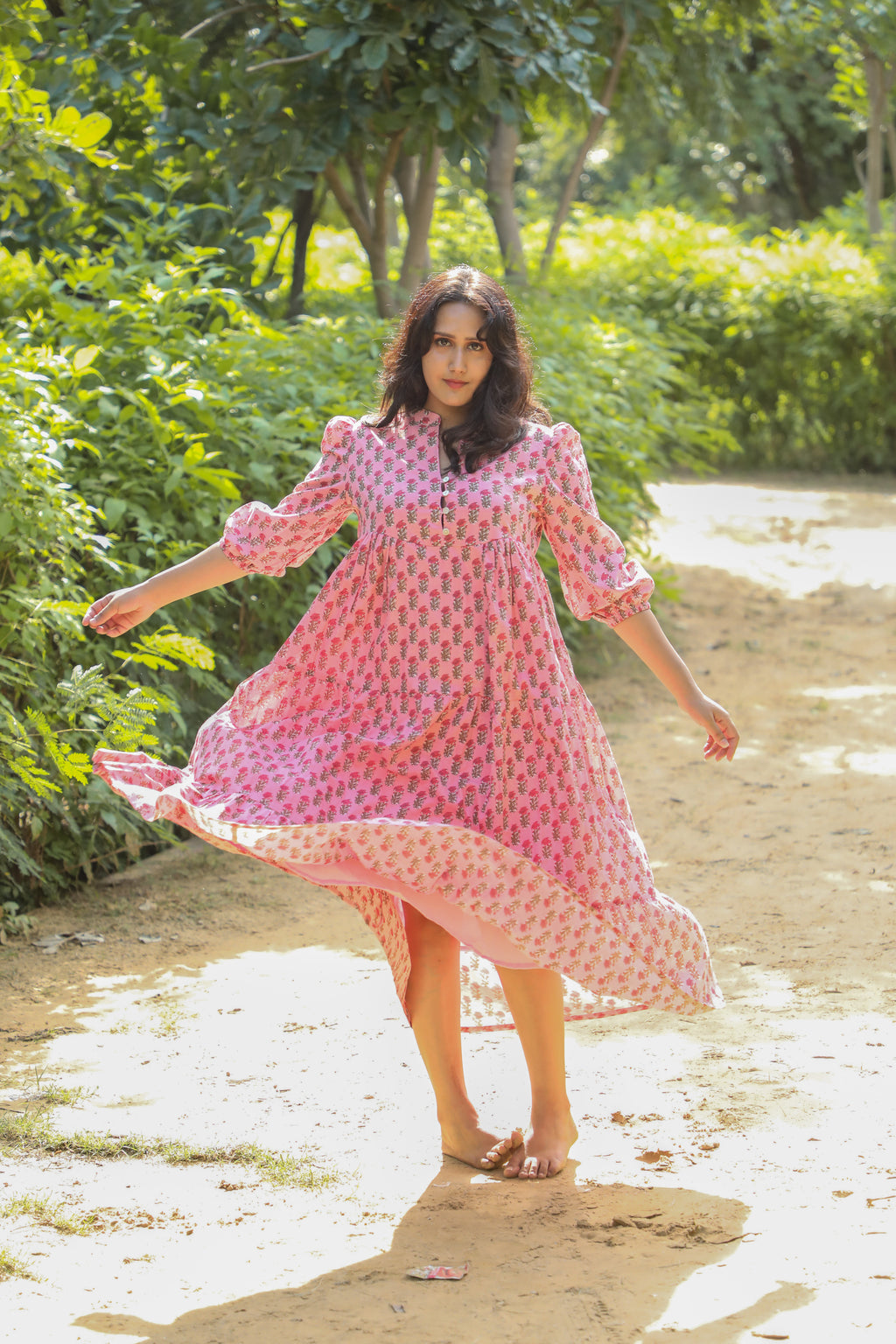 A woman is seen running or dancing in a pinkish floral printed handmade cotton mini dress in an outdoor setting.