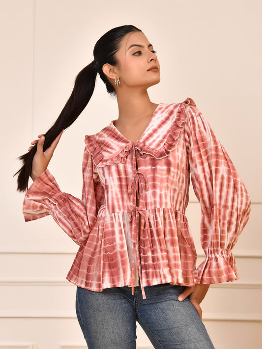 Woman wearing a pink and white checkered blouse with blue jeans against a neutral background