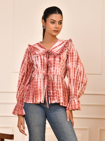 Woman wearing a red and white checkered blouse with blue jeans against a neutral background