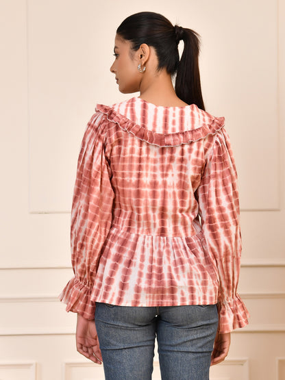 Person wearing a red and white tie-dye blouse with ruffled details on a beige background