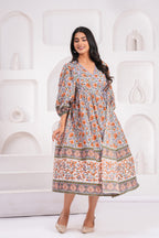 Woman wearing a floral dress standing against a white geometric-patterned wall.