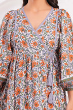 Close-up of a floral dress with orange and green patterns on a white background
