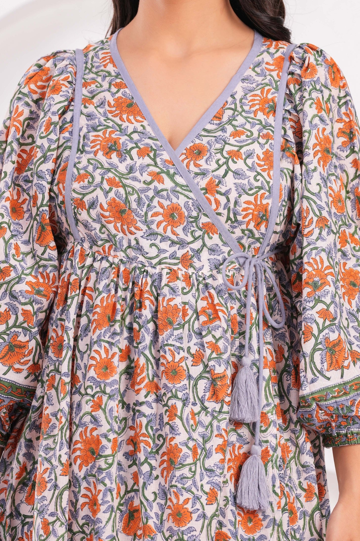 Close-up of a floral dress with orange and green patterns on a white background